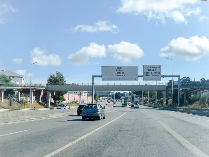 Cars and a lorry under overhead signs for the IC19 to Lisbon and the Cacem exit on the motorway west of Lisbon