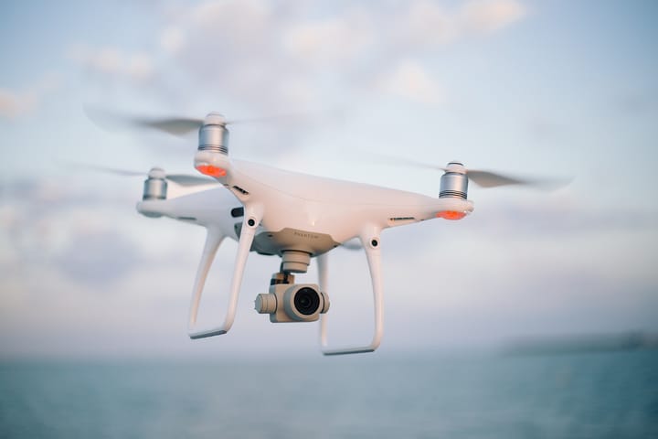 A white camera drone in flight over the sea