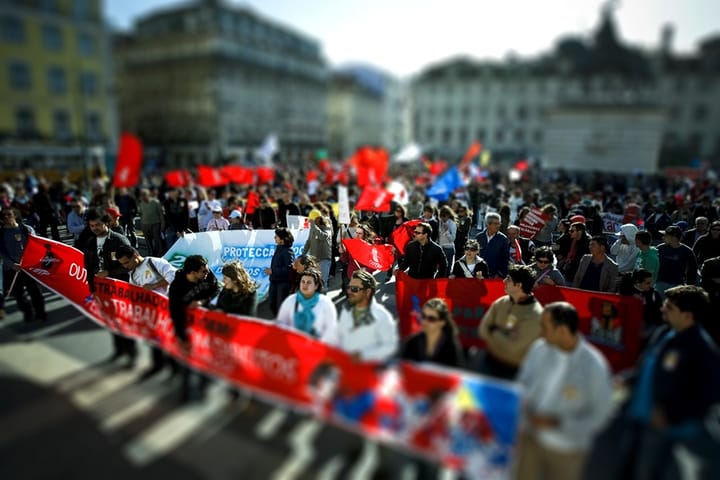 CGTP trade union demonstration in a Lisbon square, with marchers carrying long red banners and red flags