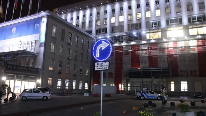 Hospital de Santa Maria in Lisbon at night, with a road sign reading Excepto viaturas de emergência and a police car at the entrance