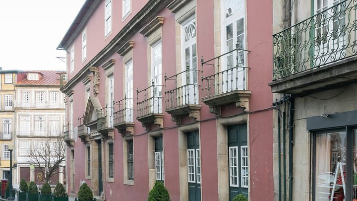 The pink baroque facade of the Guimaraes Court of Appeal on a cobbled street, with stone-framed windows, wrought-iron balconies and an armorial portal