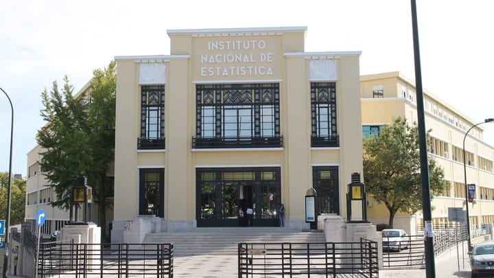The art deco facade of the Instituto Nacional de Estatistica headquarters in Lisbon, a cream building with its name in capitals above tall dark-framed windows