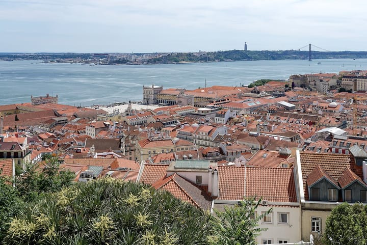 Lisbon seen from the Castelo de Sao Jorge, the tiled roofs of the Baixa running down to the Praca do Comercio, with the Tagus, Almada and the 25 de Abril bridge beyond