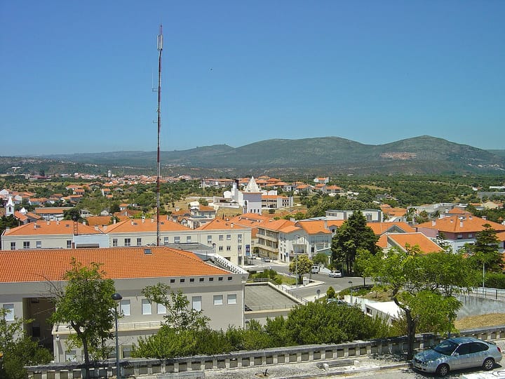 A view over the rooftops of Alcanena in Santarém district, orange tiles and white houses with the low serra rising behind under a clear blue sky