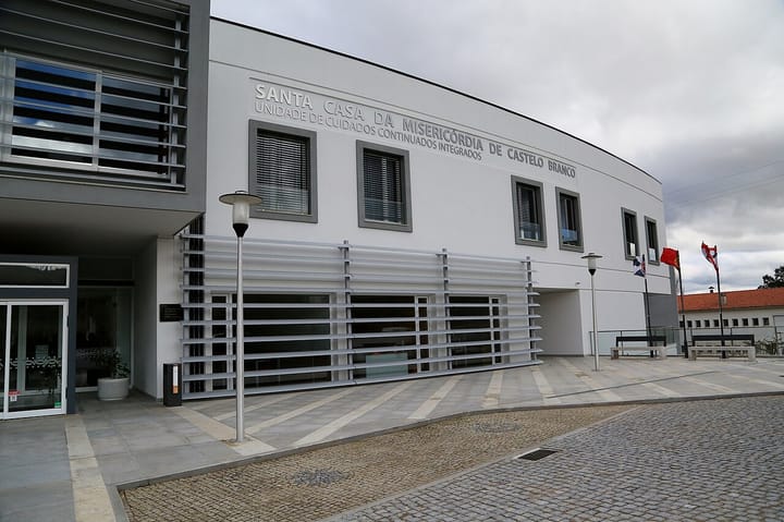 The white modern facade of the Santa Casa da Misericórdia de Castelo Branco integrated continuing-care unit, its name in raised letters, under a grey sky