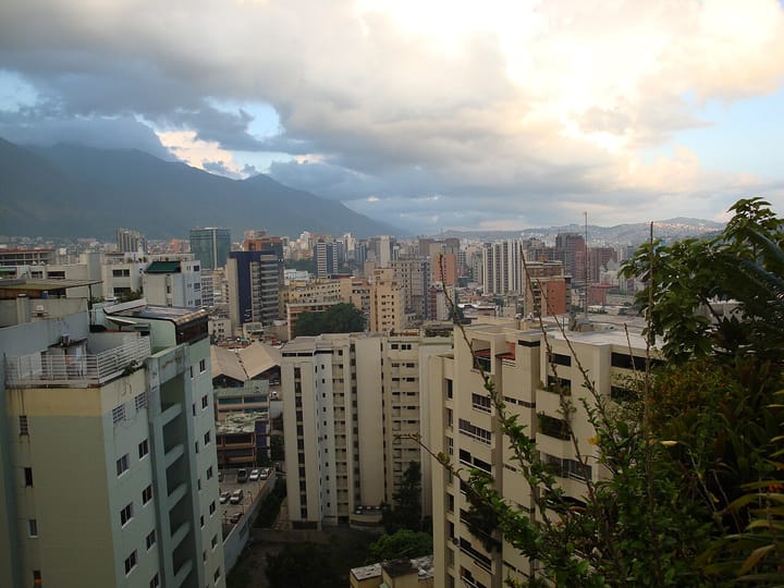 Apartment towers of Caracas under a cloudy sky, with the green slopes of the Ávila mountain on the left