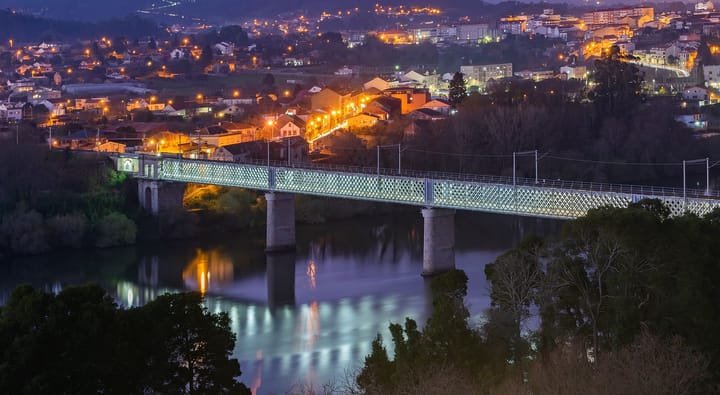 The old iron international bridge over the river Minho between Valença and Tui, lit up at dusk
