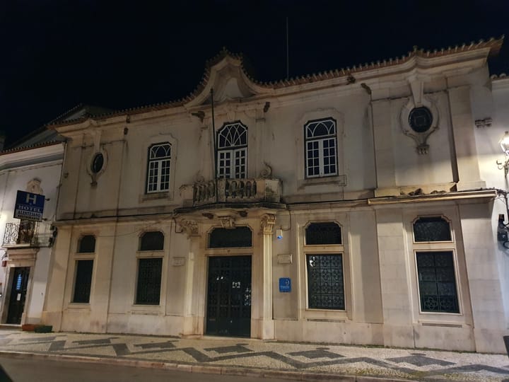 The baroque stone facade of the tax office in Estremoz at night, with the blue Finanças sign beside the door