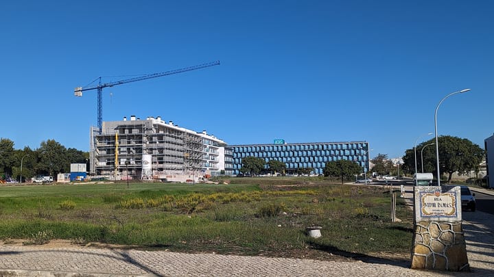 A tower crane over a new apartment block under construction beside an office building in Carcavelos, near Lisbon