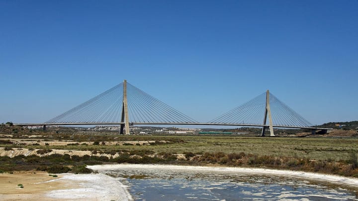 The cable-stayed Guadiana International Bridge, which links the Algarve with Andalusia, seen across salt marsh under a clear blue sky