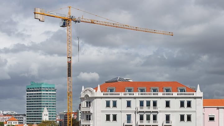 A yellow construction crane above a white apartment building on Alameda Afonso Henriques in Lisbon
