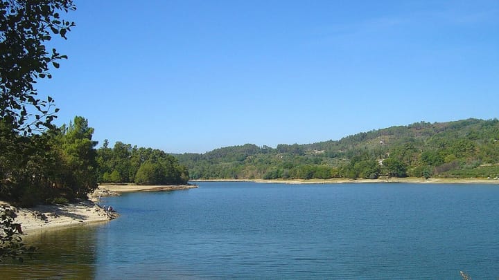 The Fagilde reservoir near Viseu, with sandy banks exposed below a wooded shoreline