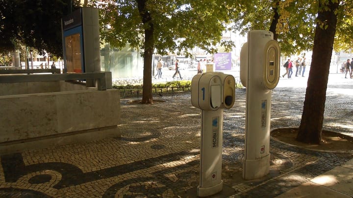 White MOBI.E electric car charging posts on the cobbled pavement of Avenida da Liberdade in Lisbon