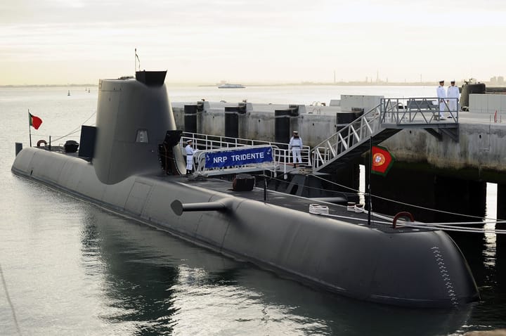 The Portuguese Navy submarine NRP Tridente moored at a pier at the Alfeite naval base, with sailors in white uniforms on deck