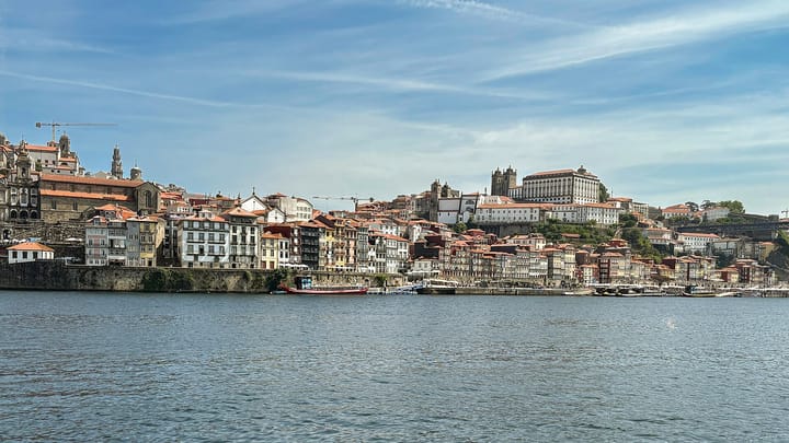 Porto's Ribeira waterfront seen across the Douro, with colourful terraced houses climbing to the cathedral towers